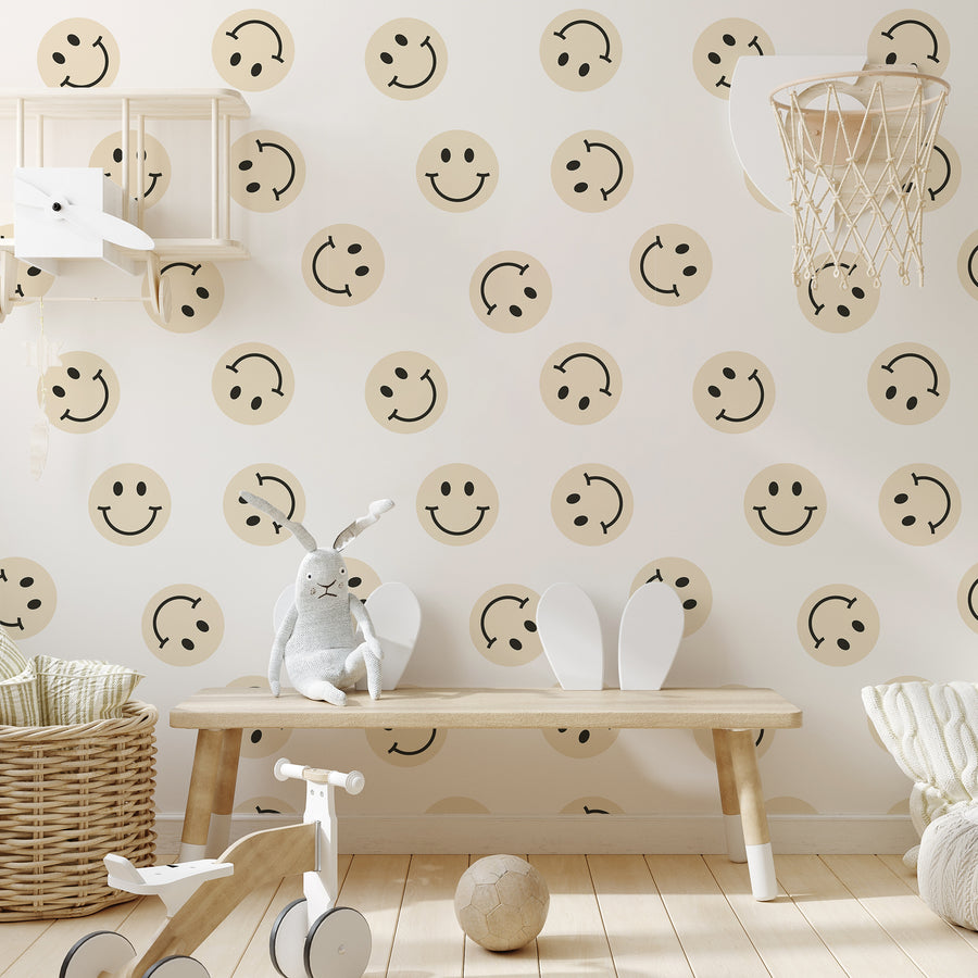 A child's playroom with a light coloured bench and toys, showing 'Diane' which is a retro wallpaper featuring repeating smiley face designs in soft pastel yellow with black facial details on a light cream background.