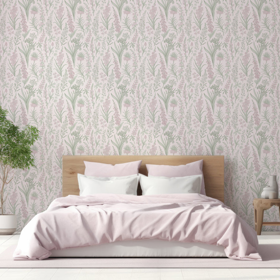A bedroom with a light wooden bedframe with light pink bedding on top of it showing 'Esther' which is a Victorian-inspired wallpaper featuring delicate pink foxglove flowers, green leaves and botanical stems on a soft pale pink background in a repeating floral pattern.