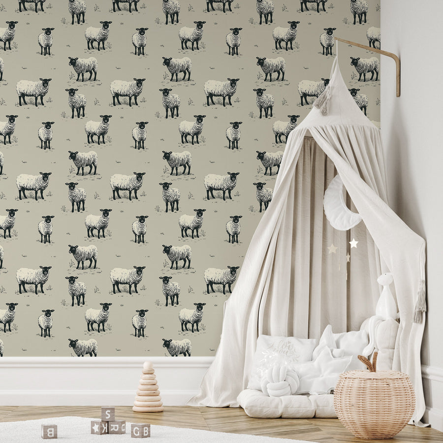 A childrens nursery with wooden toys featuring 'Mary' which is a wallpaper featuring hand-drawn sheep grazing in a meadow with wildflowers, rolling hills and countryside scenery in a charming repeating pattern.