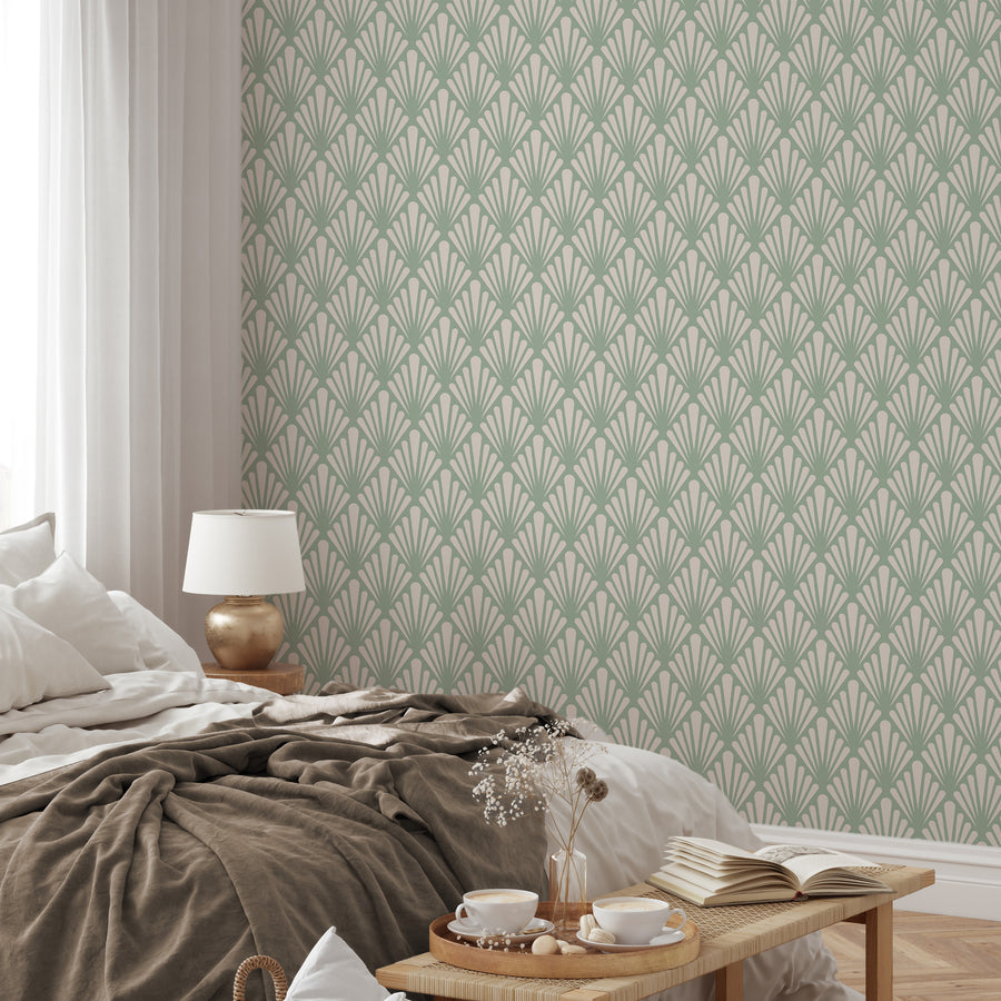 A bedroom with natural coloured bedding on top featuring 'Virginia Cambridge' which is a green Art Deco wallpaper featuring stylised fan-shaped leaves and geometric botanical motifs in a vintage-inspired repeating pattern.