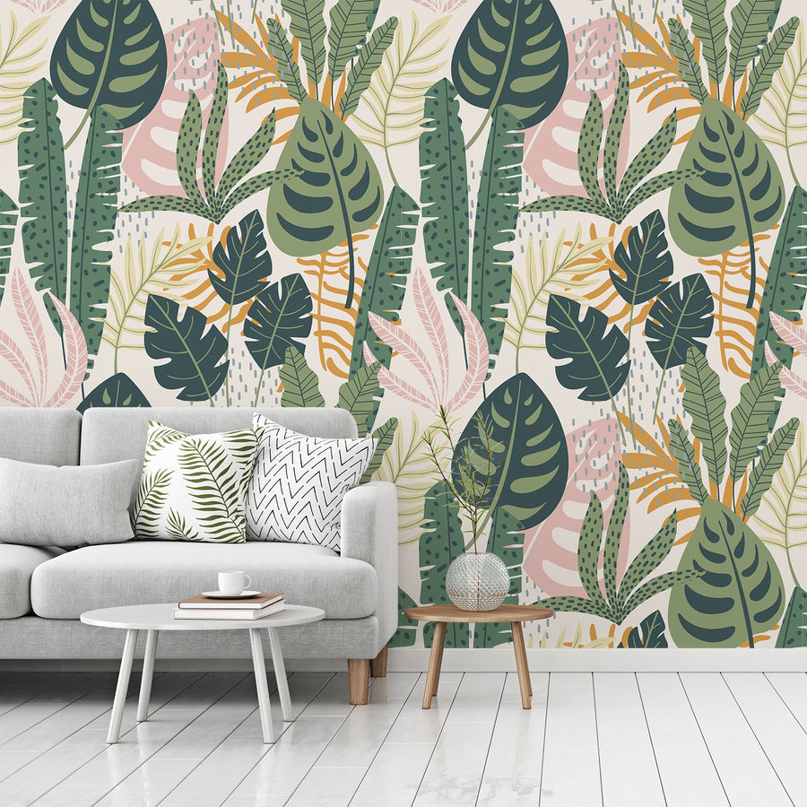 A living room with a light grey coloured sofa and small side tables showing 'Heather' which is tropical rainforest wallpaper featuring lush green leaves, exotic plants and dense jungle foliage in a vibrant botanical repeating pattern.